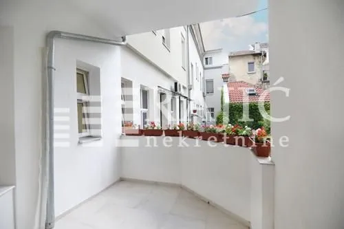 Spacious white terrace with flower boxes and a view of buildings.