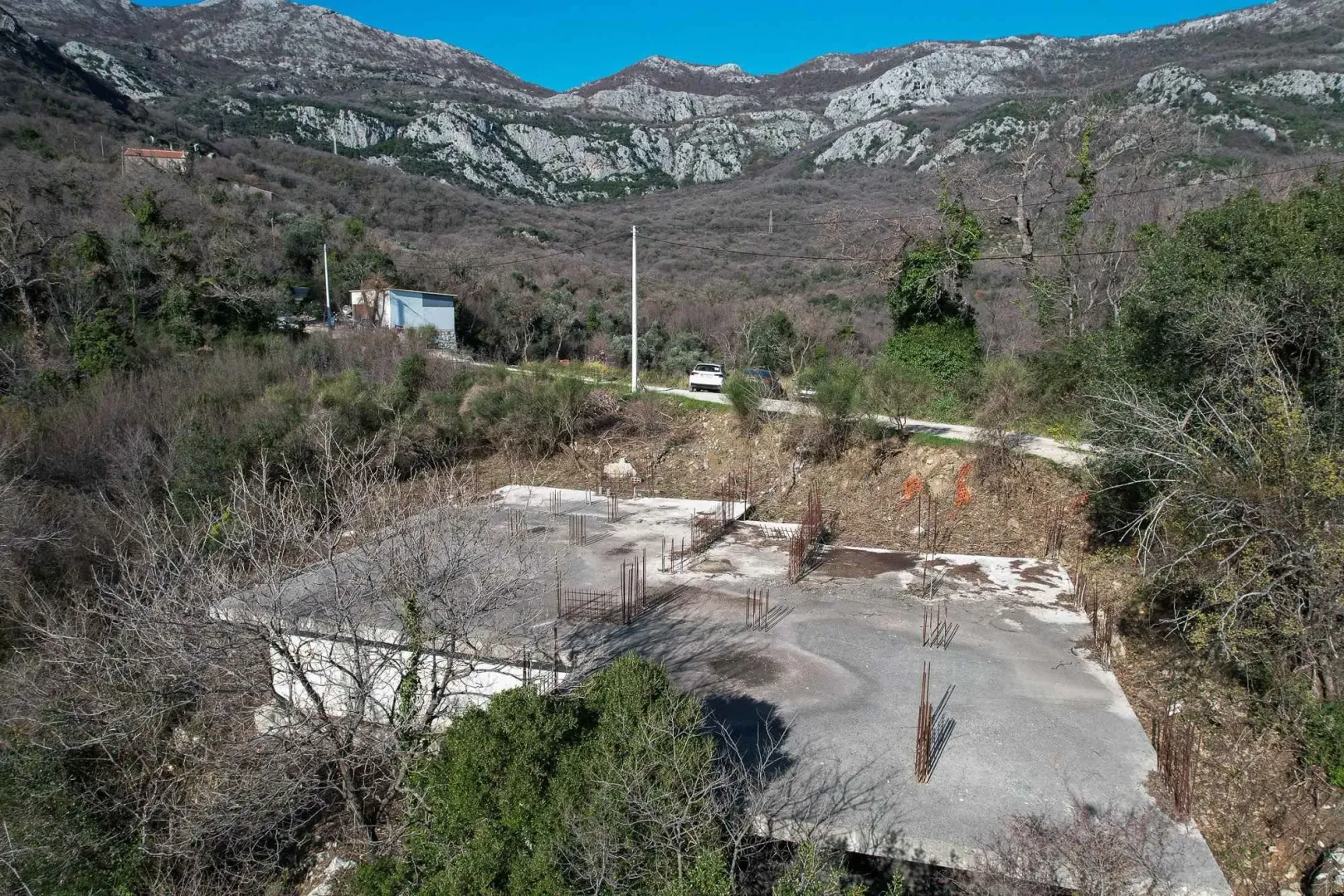 Pogled iz vazduha na betonsku ploču objekta u izgradnji okruženog prirodom.