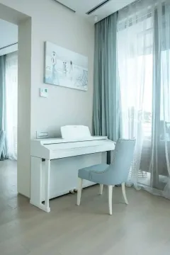 Dnevna soba sa bijelim klavirom i udobnom foteljom pored prozora. - image 2