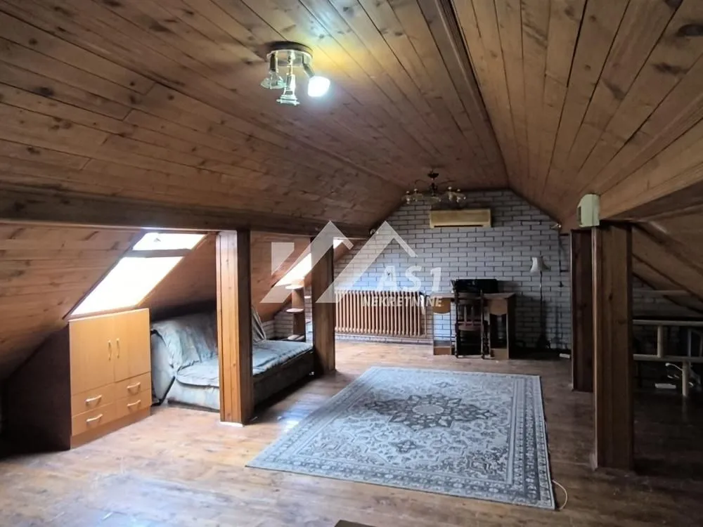 Attic space with wooden paneling on the walls and ceiling, and a rug on the floor.