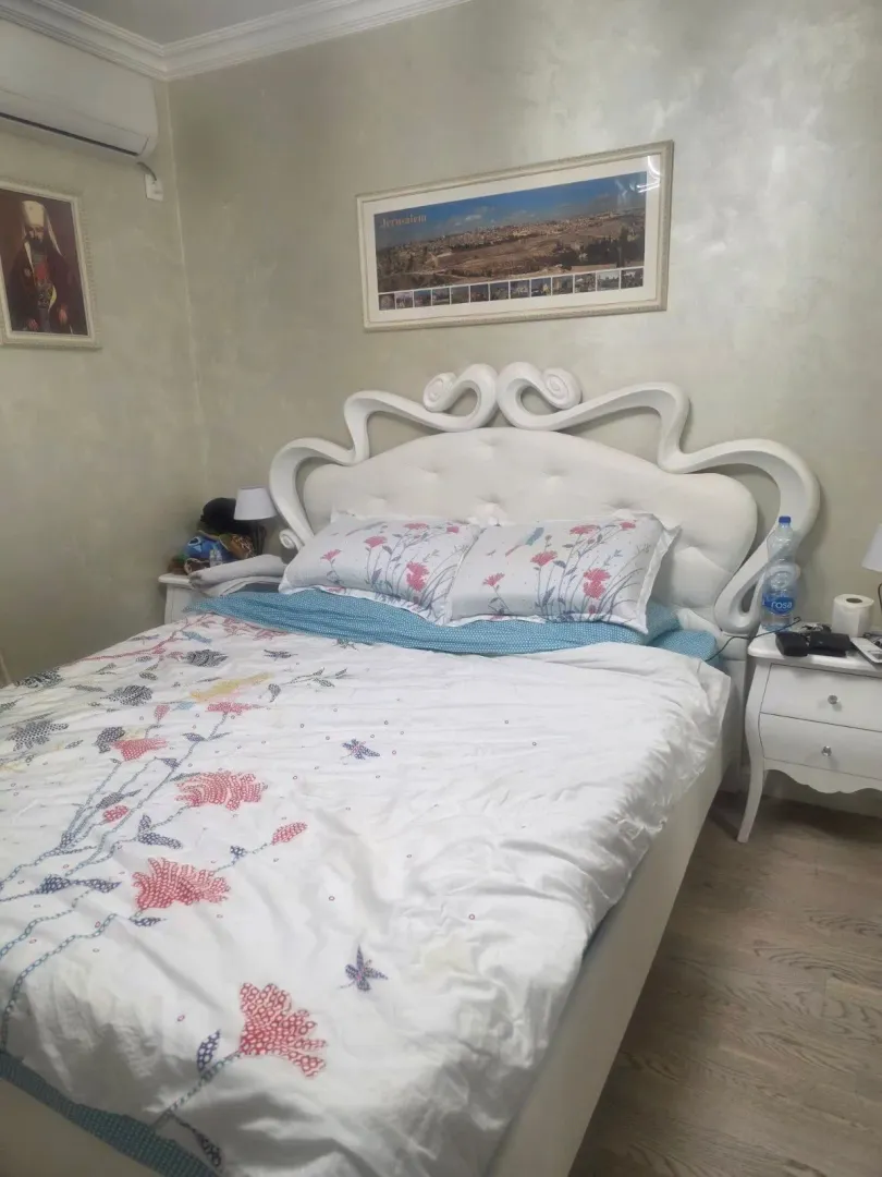 Spavaća soba sa velikim bračnim krevetom i bijelim noćnim stočićima.