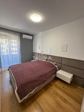 Spavaća soba sa bračnim krevetom, drvenim podom i izlazom na balkon. - image 5