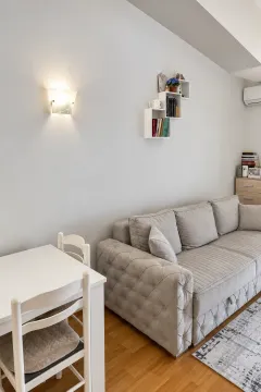 Dnevni boravak sa udobnom sivom garniturom i bijelim trpezarijskim stolom. - image 8