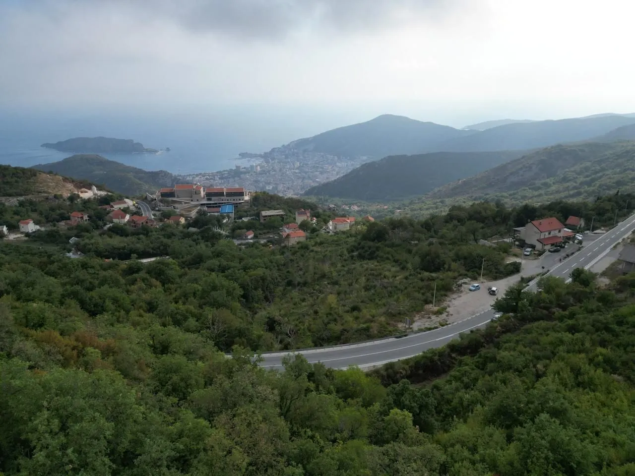 Pogled iz ptičje perspektive na planinski krajolik, grad i more u daljini.