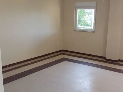 An empty room with tiled flooring and a single window. - image 3