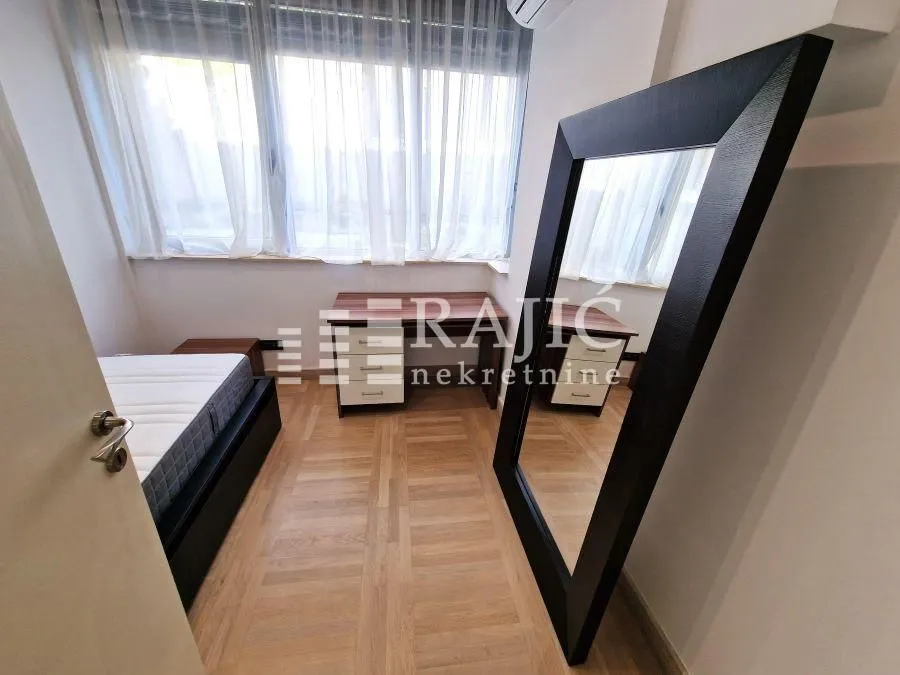 Furnished bedroom with a bed and a large mirror.