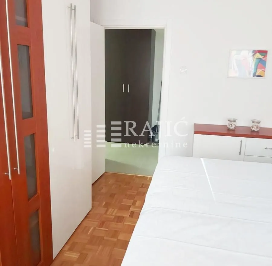 Furnished bedroom with a double bed, wardrobe, and parquet flooring.