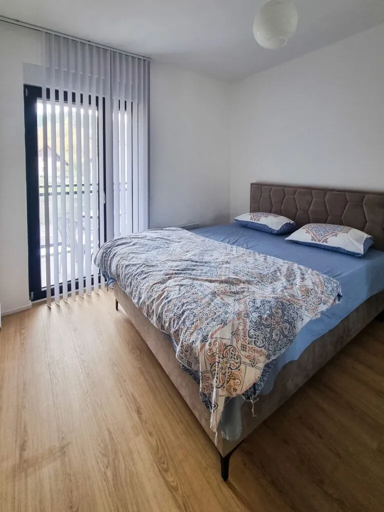 Svjetla spavaća soba sa bračnim krevetom i izlazom na terasu.
