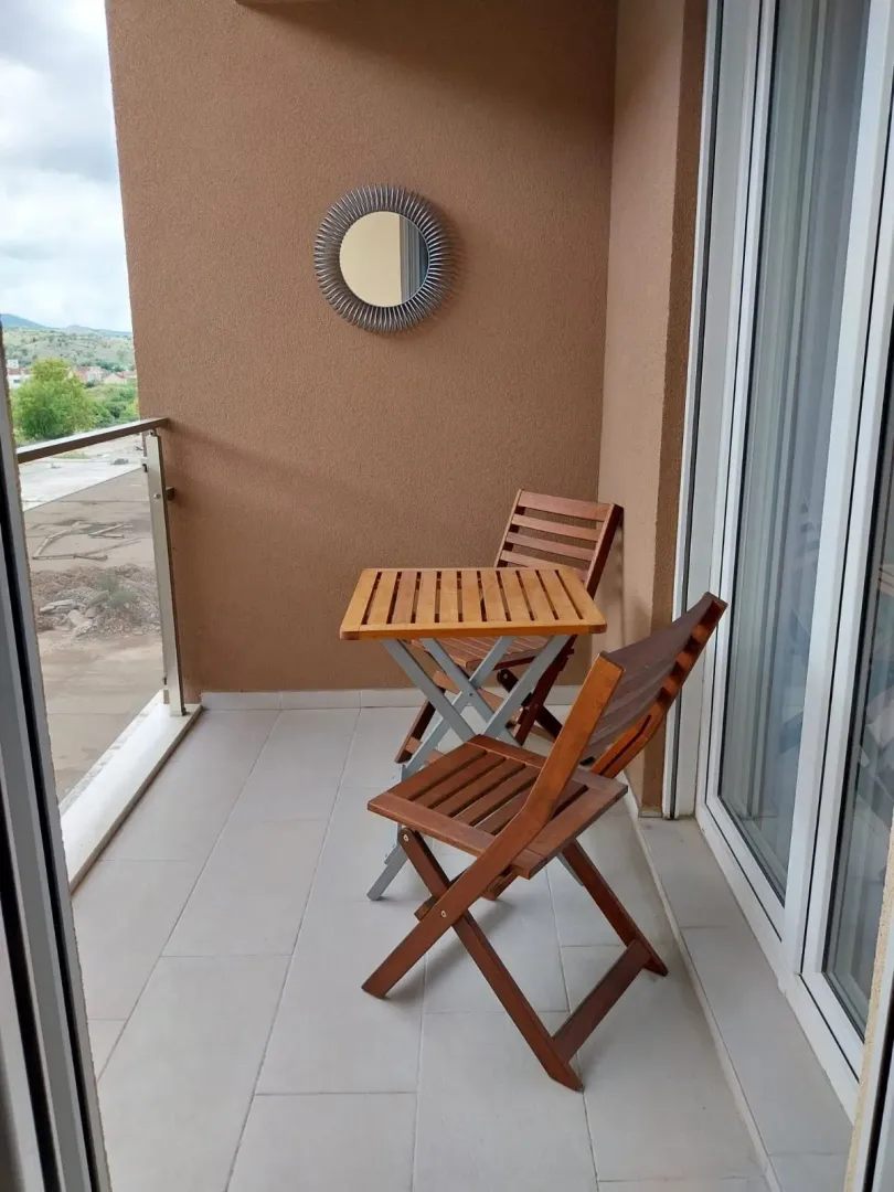 Balcony with a wooden table and two chairs.
