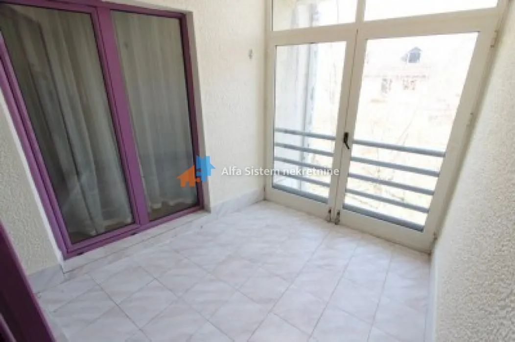 Natkriveni balkon sa popločanim podom i velikim balkonskim vratima.