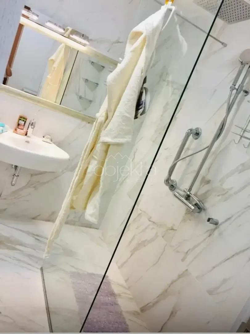 Modern bathroom with a walk-in shower tiled in marble.