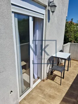Small tiled balcony with a table and two chairs next to the balcony door. - image 9