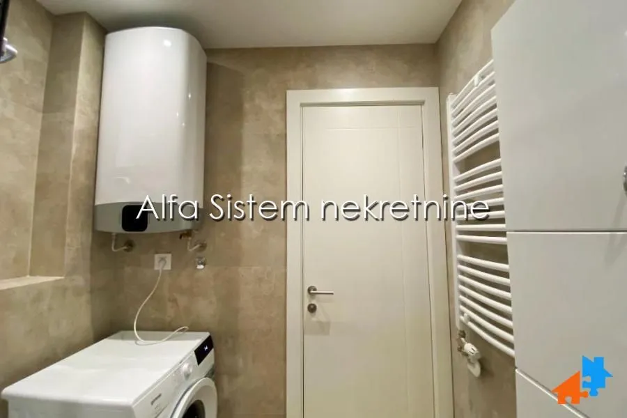 Bathroom with water heater, washing machine and towel rail.