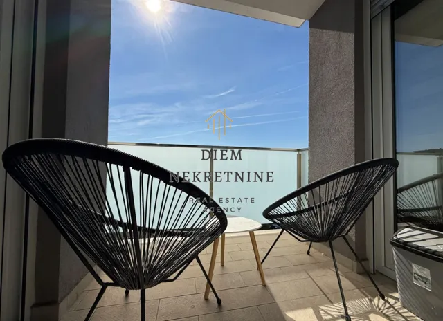 Furnished balcony with two black chairs and a view of the sky.