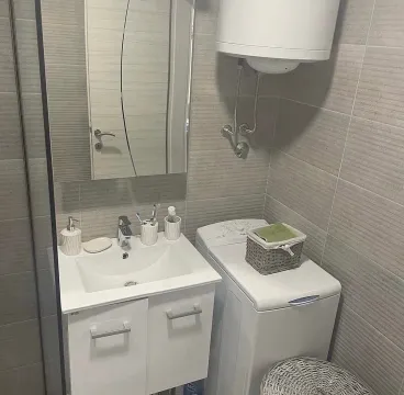 Small bathroom with a sink, mirror, and washing machine. - image 7
