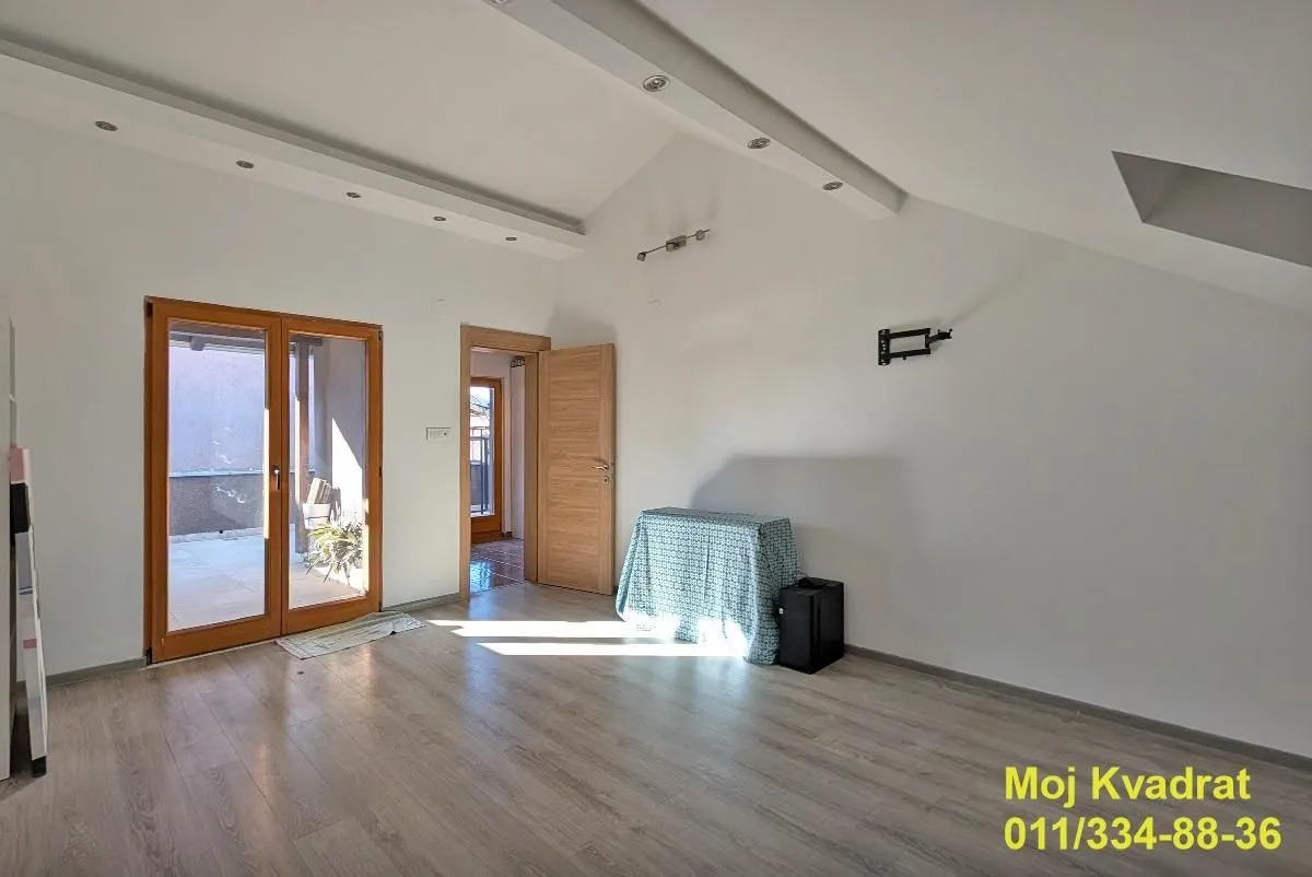 Empty room with wooden flooring, drop ceiling, and access to a terrace.
