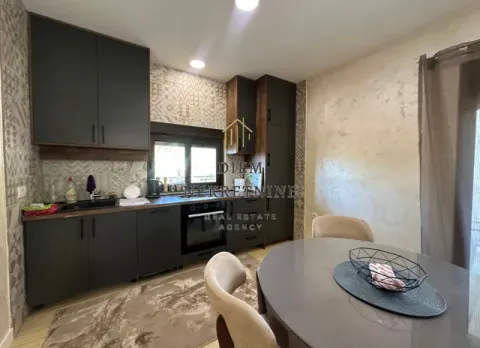 Modern kitchen with dark cabinetry and a dining table. - image 5