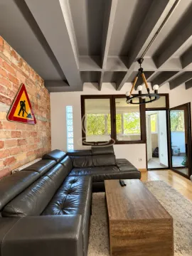 Living room with a black leather sofa, brick wall, and wooden coffee table. - image 2
