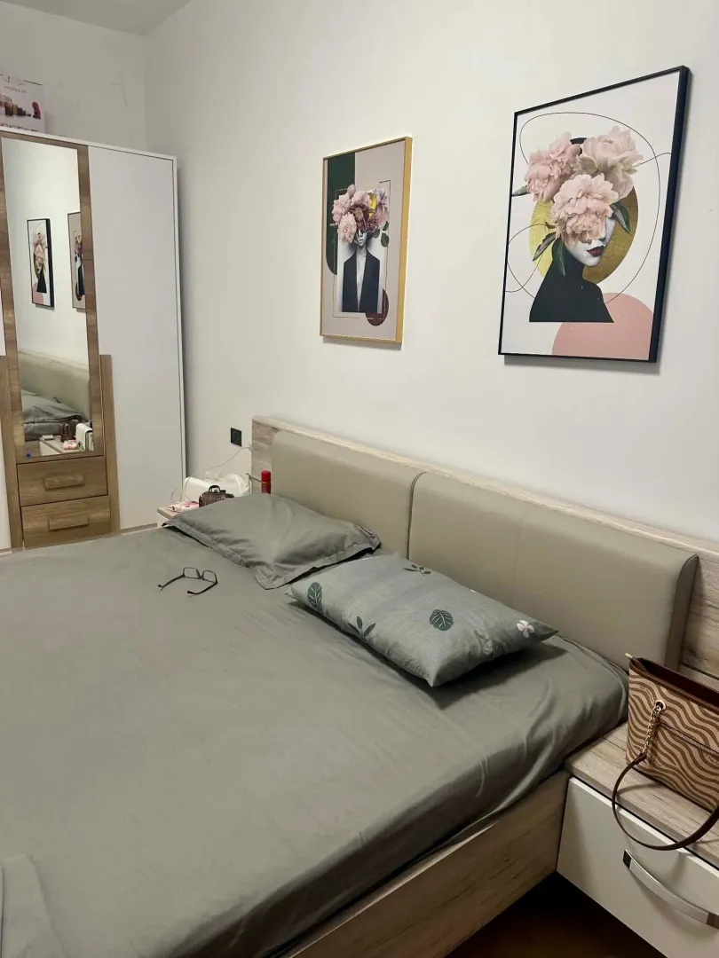 Furnished bedroom with a double bed, wardrobe, and wall paintings.