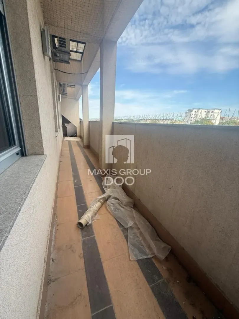 Long covered balcony with tiled flooring and a railing.