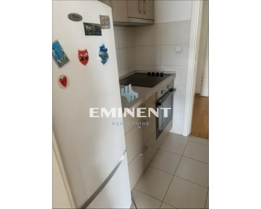 Manja kuhinja sa belim frižiderom i ugradnim elementima.