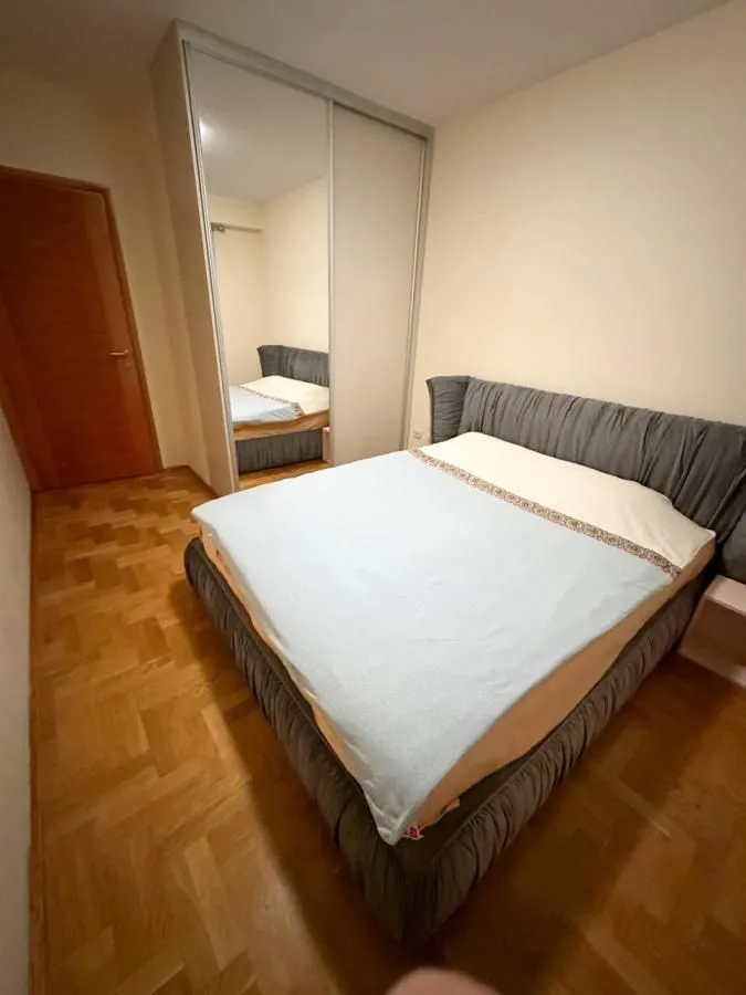 Spavaća soba sa bračnim krevetom i ugradnim plakarom sa ogledalom.