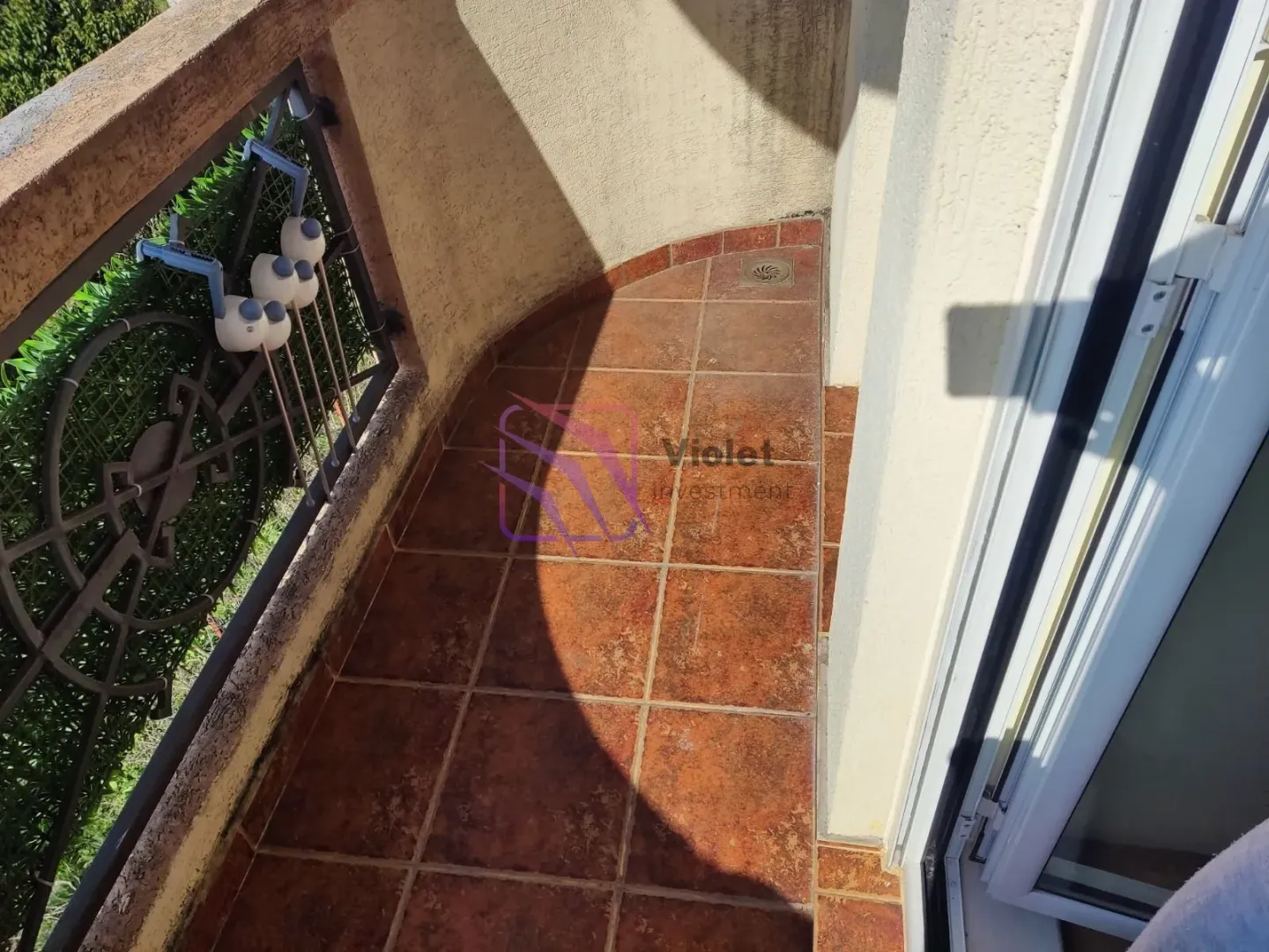 Pogled na manji popločani balkon sa metalnom ogradom.
