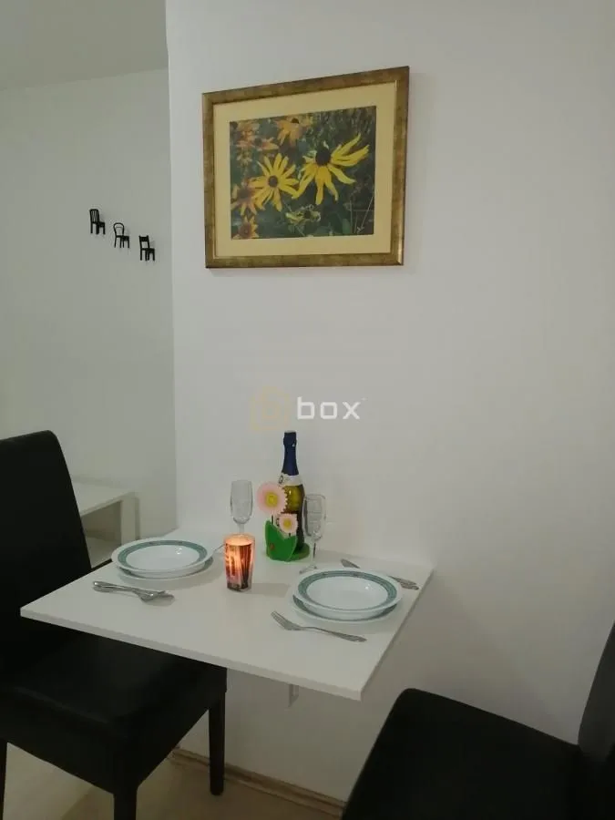Small dining table with set plates and a bottle of drink.