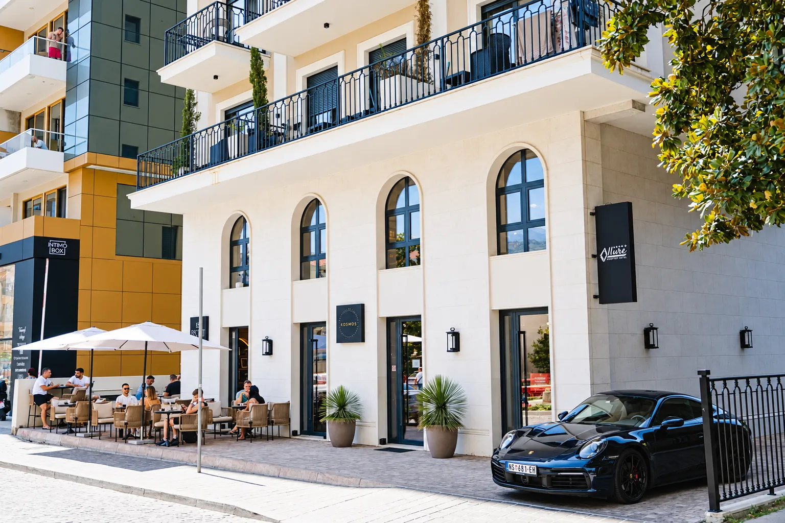Exterior view of a modern residential and commercial building with terraces and a ground floor venue.