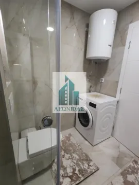 Bathroom with a shower cabin, toilet, washing machine, and water heater. - image 14