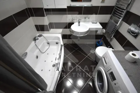 Bathroom equipped with a bathtub, washbasin, toilet, and washing machine. - image 9
