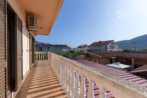 Dugački balkon sa bijelom kamenom ogradom i pogledom na okolne zgrade i brda. - image 37