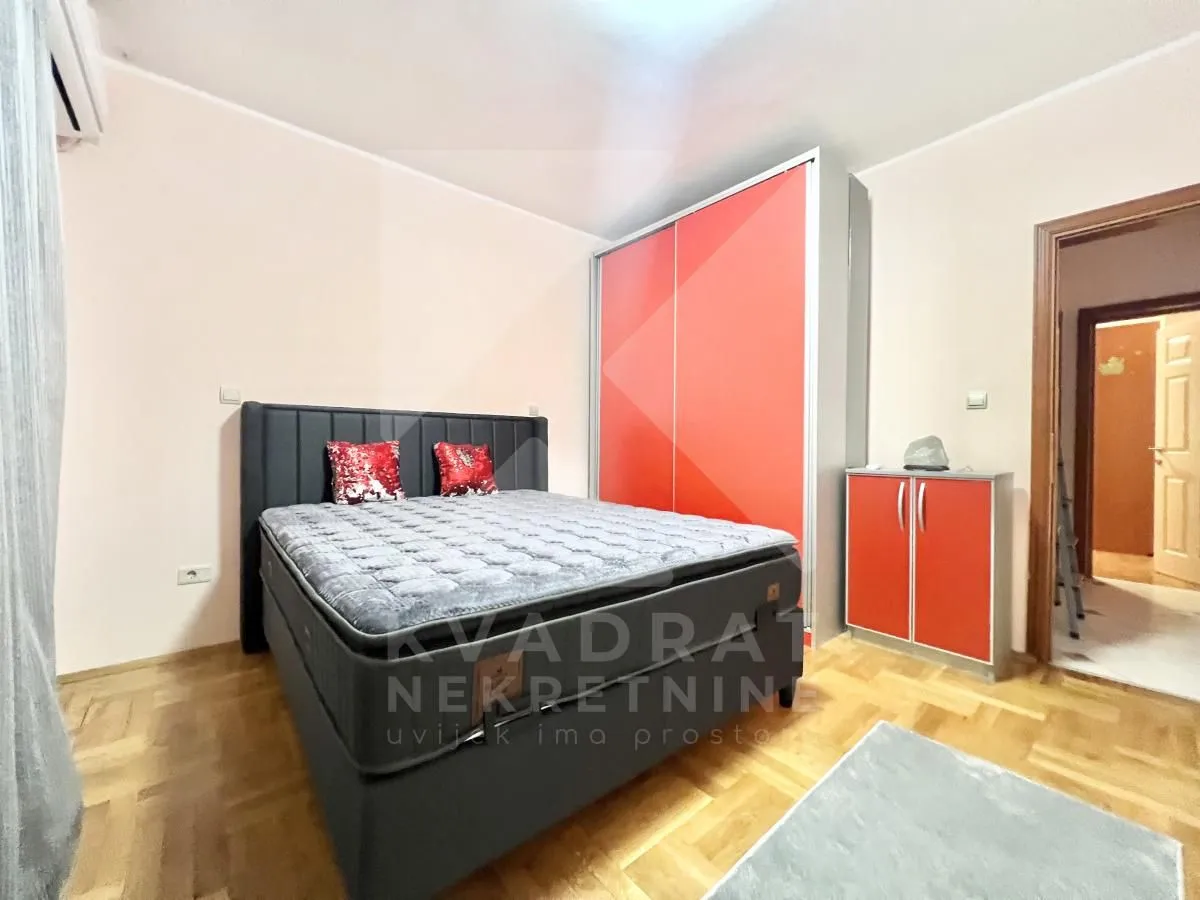 Namještena spavaća soba sa bračnim krevetom i ormarom.