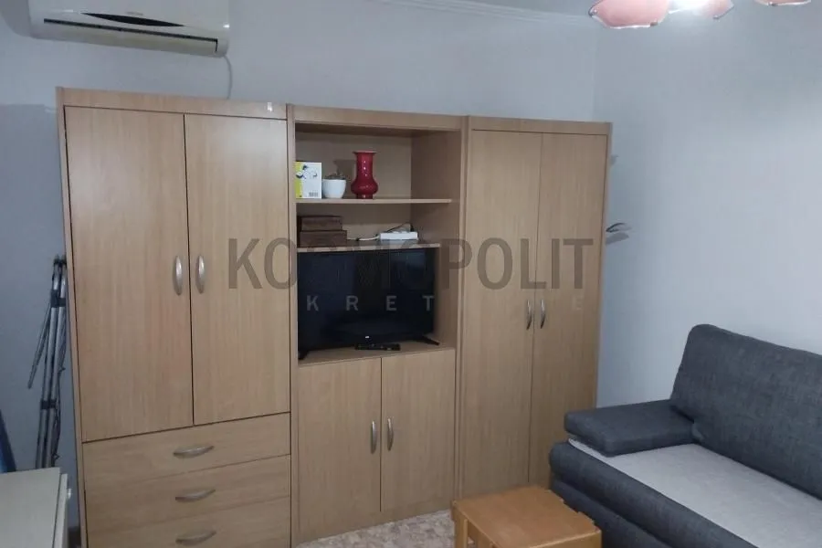Living room with a large wooden wardrobe, television and a sofa.