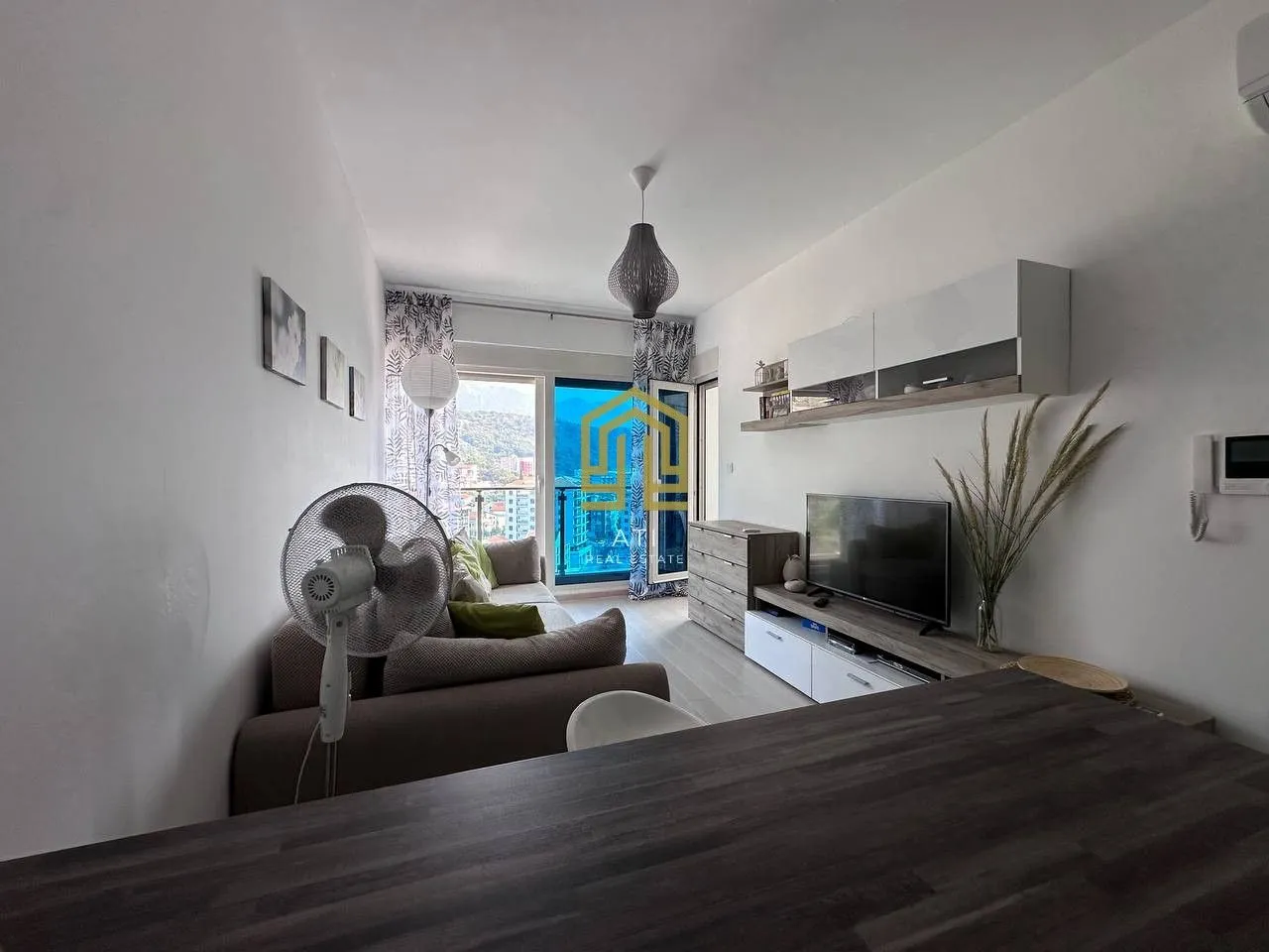 Living room with sofa, television, and balcony access.