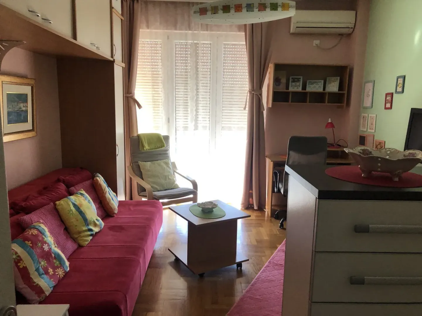 Living room featuring a pink sofa, armchair, and a study desk.