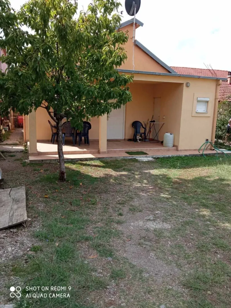 Spoljašnjost jednospratne kuće sa dvorištem i natkrivenom terasom.