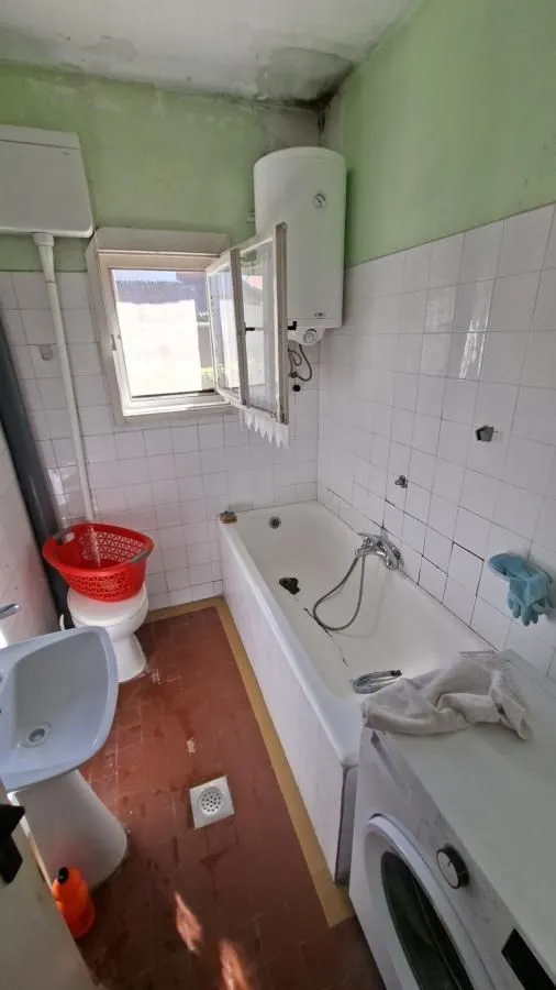 Starije opremljeno kupatilo sa kadom, umivaonikom i wc šoljom.