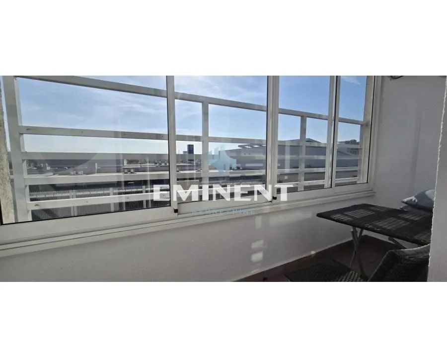 Enclosed balcony with a small table and chairs.