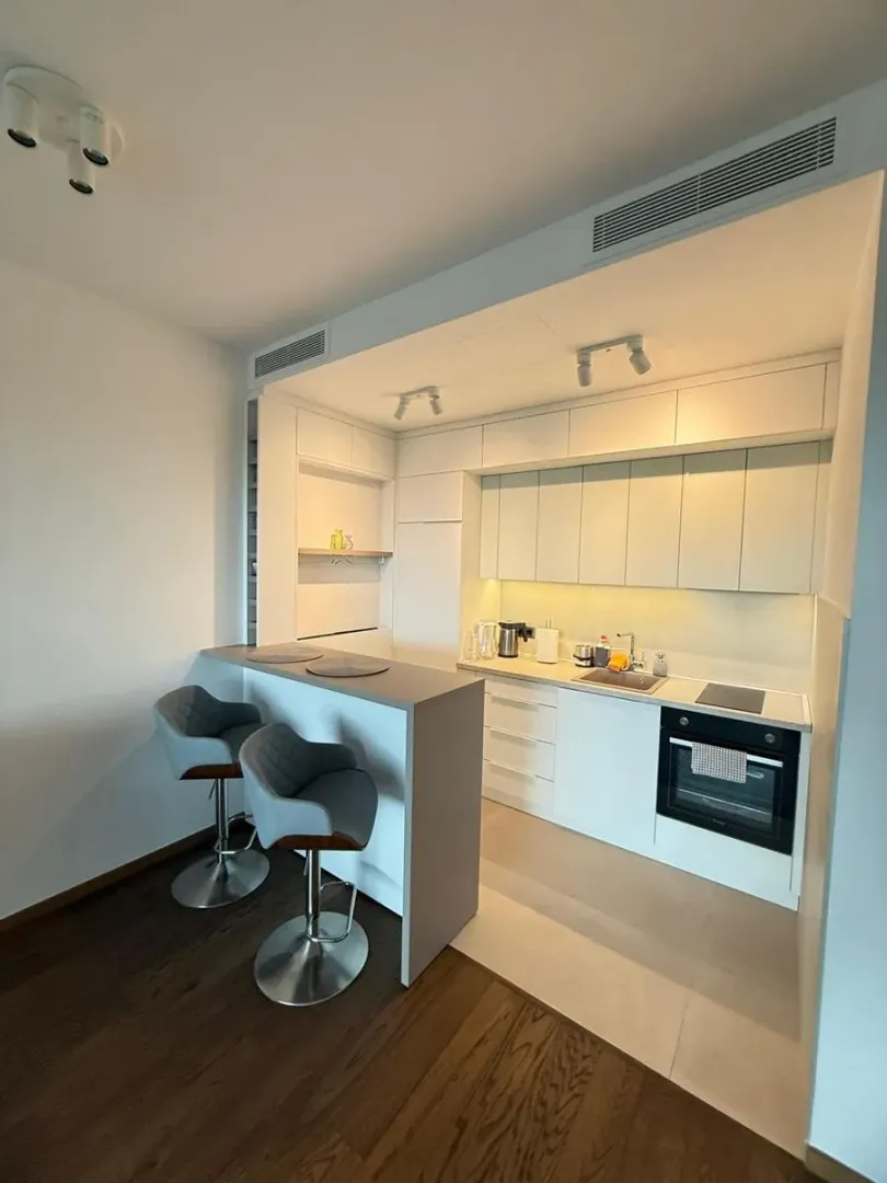 Modern white kitchen with a breakfast bar and bar stools.