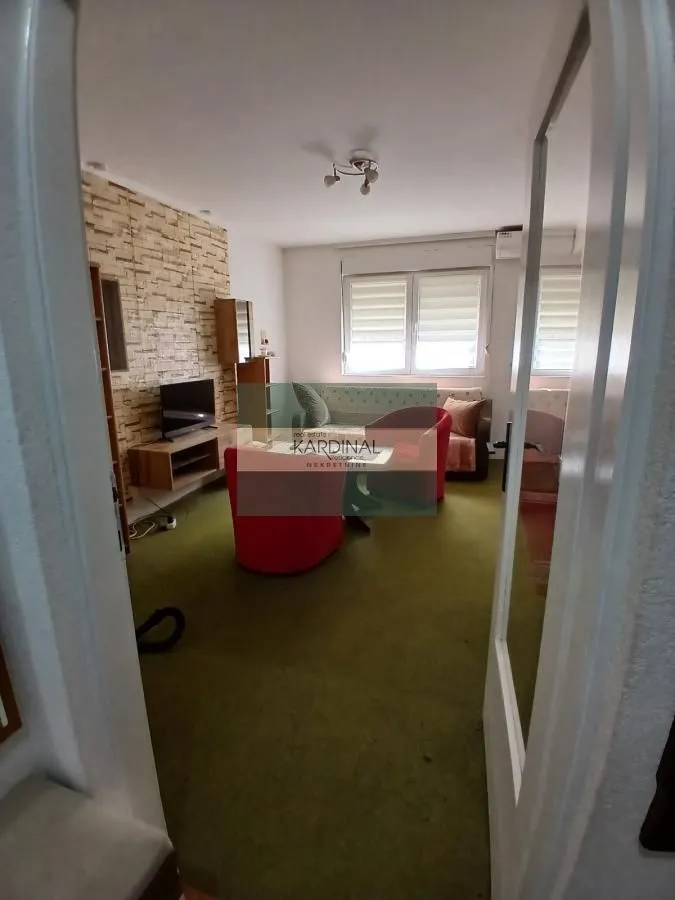 Dnevna soba sa garniturom i televizorom, gledana sa vrata.