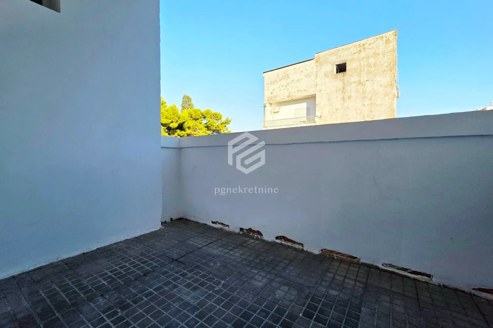 View from the tiled terrace towards surrounding buildings and the sky.