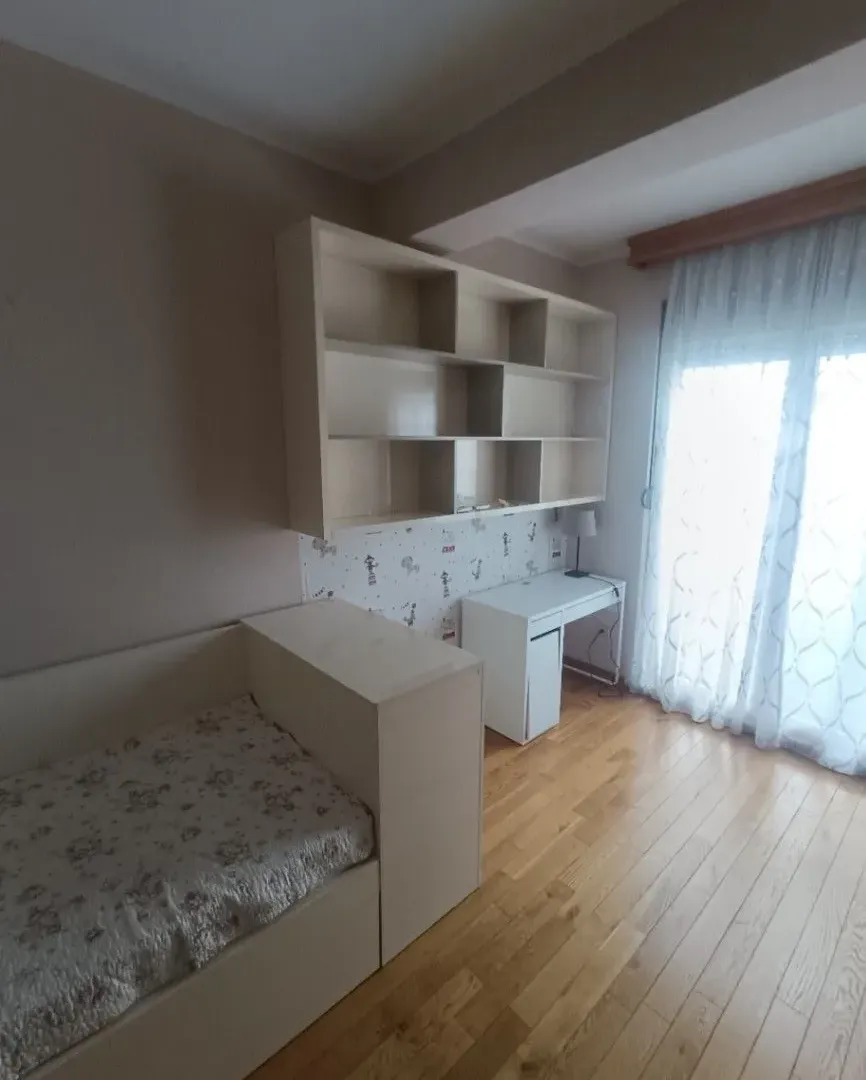 Dječja soba sa krevetom, radnim stolom, police i drvenim podom.