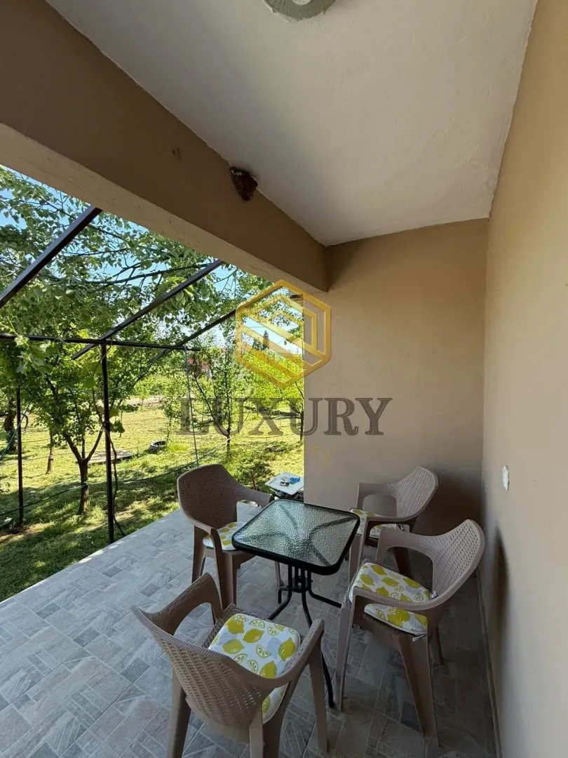 Covered terrace with seating furniture and a view of the yard.
