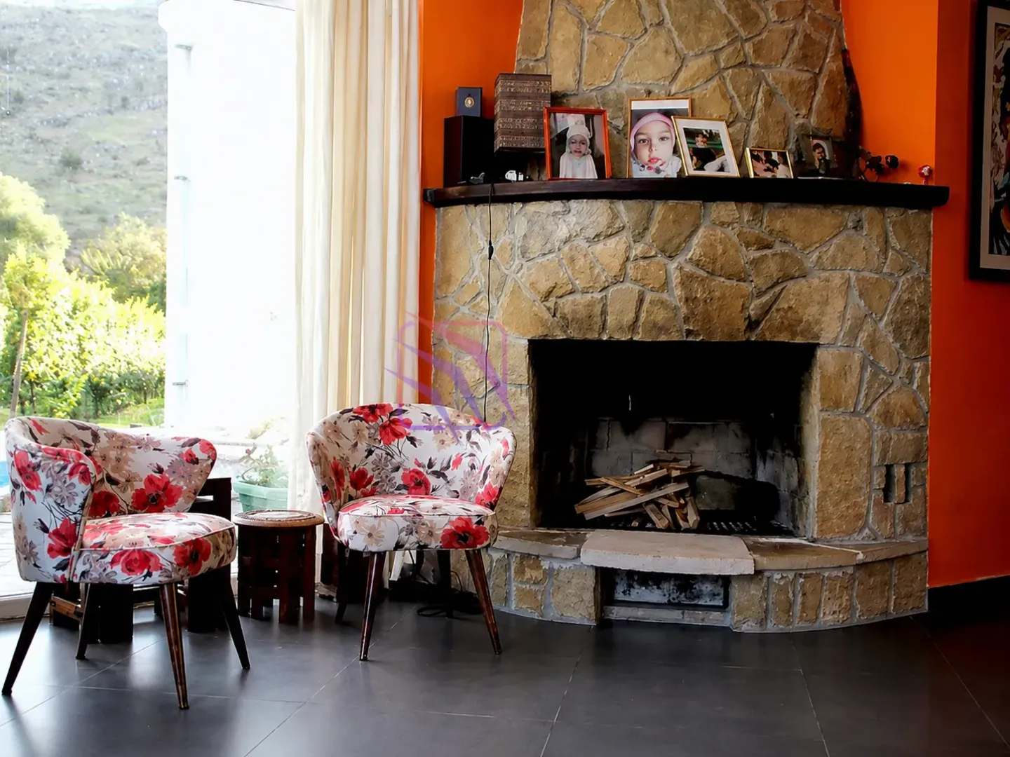 Living room with a fireplace and two armchairs with floral pattern.