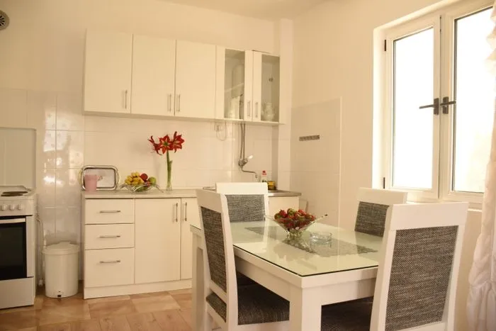 Kitchen with white cabinetry and a dining table by the window.