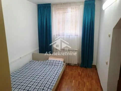 Smaller bedroom with a bed and a window with blue curtains. - image 24