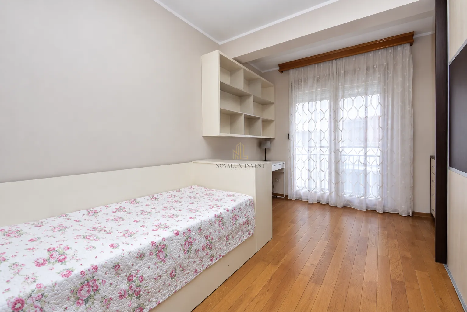Bedroom with a bed, desk, shelving unit, and balcony access.