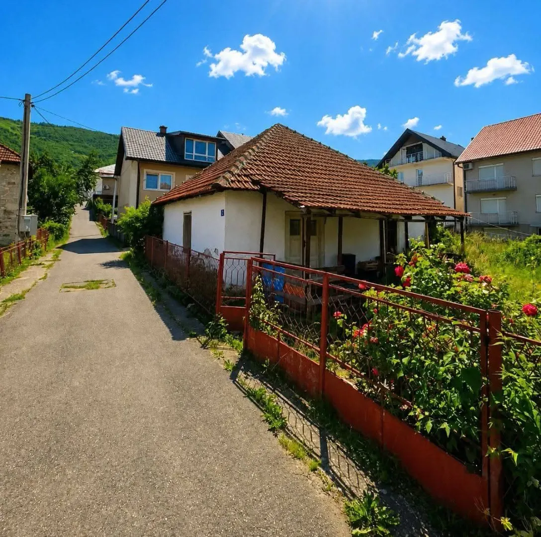 Pogled na stariju prizemnu kuću sa dvorištem i ulicom u naselju.