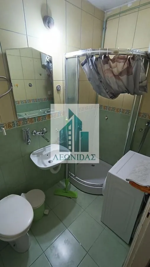 Small bathroom with a shower cabin, washbasin, toilet, and washing machine.